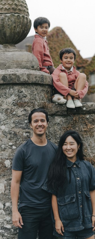 Daniel and Lucas sitting on a stone wall, with their parents Miguel and Tottie standing below